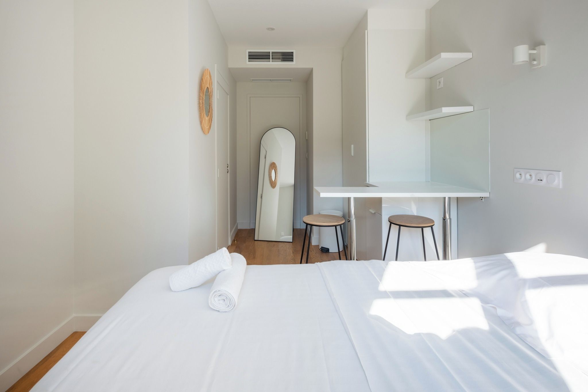 Une chambre d’hôtel avec un lit, un bureau, une chaise et un miroir.