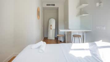 Une chambre d’hôtel avec un lit, un bureau, une chaise et un miroir.