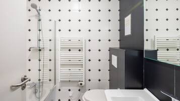 Une salle de bain moderne avec une douche à parois de verre, des toilettes blanches et un lavabo noir.