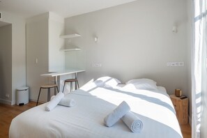 A modern hotel room with a bed, a desk, and a chair.