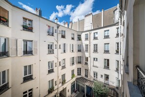 Ein mehrgeschossiges Gebäude mit Balkonen, Fenstern und einem sichtbaren Eingang im Erdgeschoss.