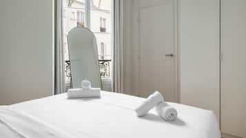Ein Hotelzimmer mit einem Bett, einem Spiegel und Blick auf Gebäude durch das Fenster.