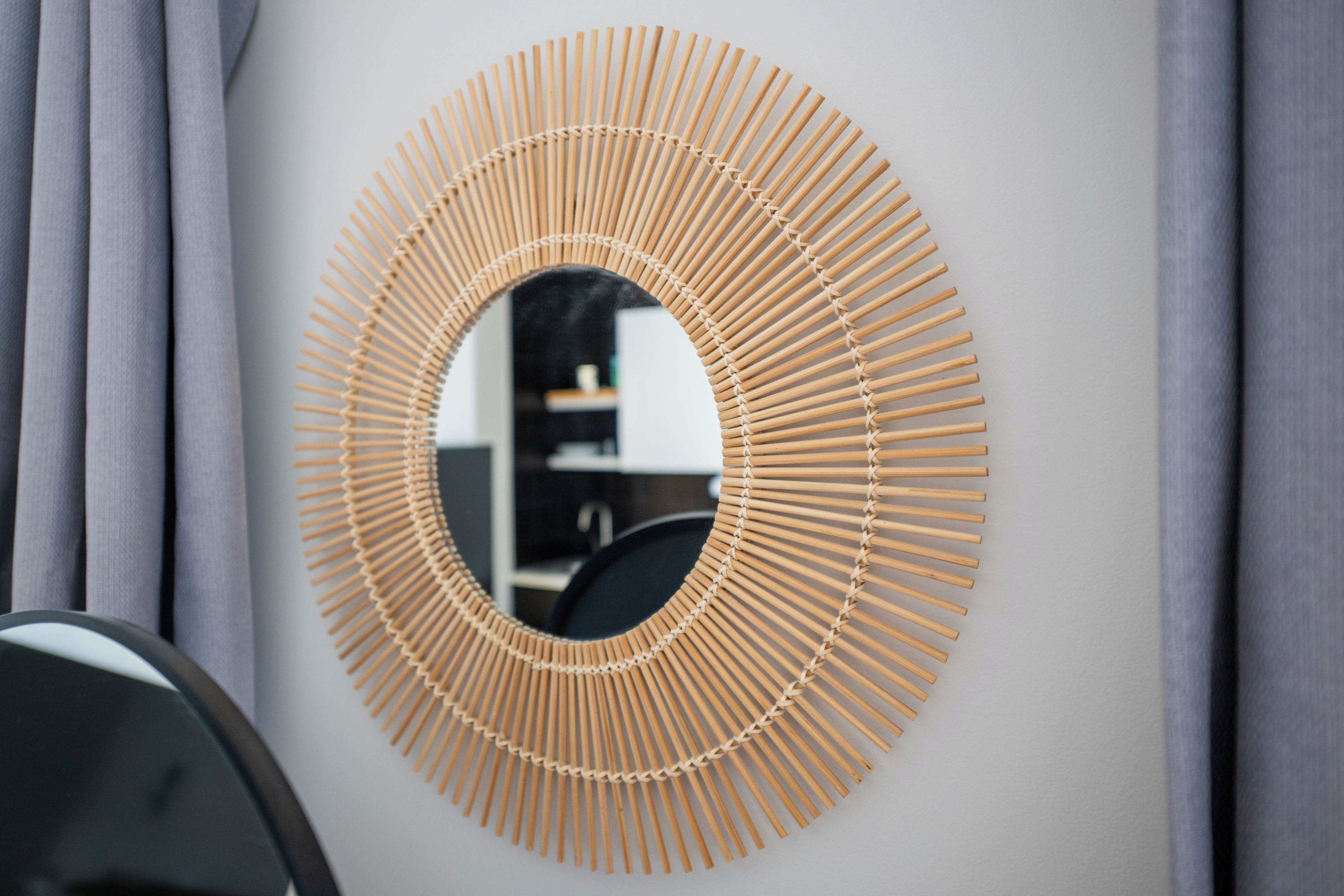 Un miroir rond avec un cadre en bambou.