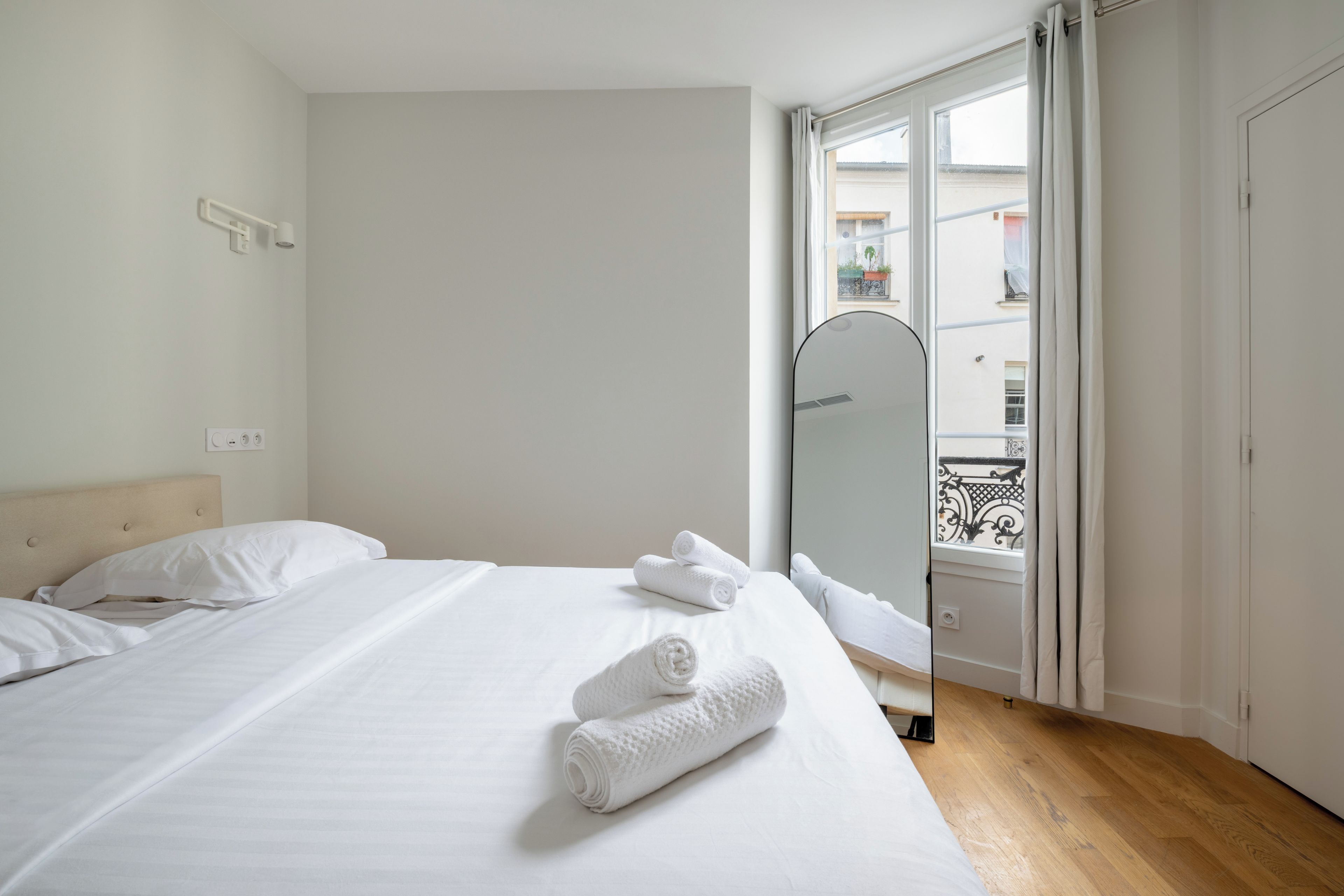 Une chambre d’hôtel avec un lit, un miroir et une vue sur le balcon extérieur.
