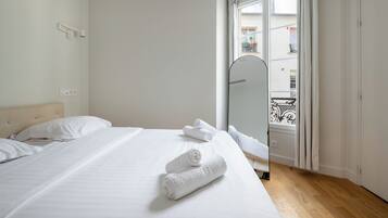 Une chambre d’hôtel avec un lit, un miroir et une vue sur le balcon extérieur.