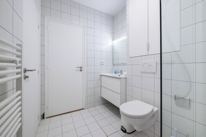 A modern bathroom with a toilet, sink, and a glass shower enclosure.