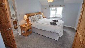 A bedroom with a wooden bed, bedside lamps, a window, and a door.