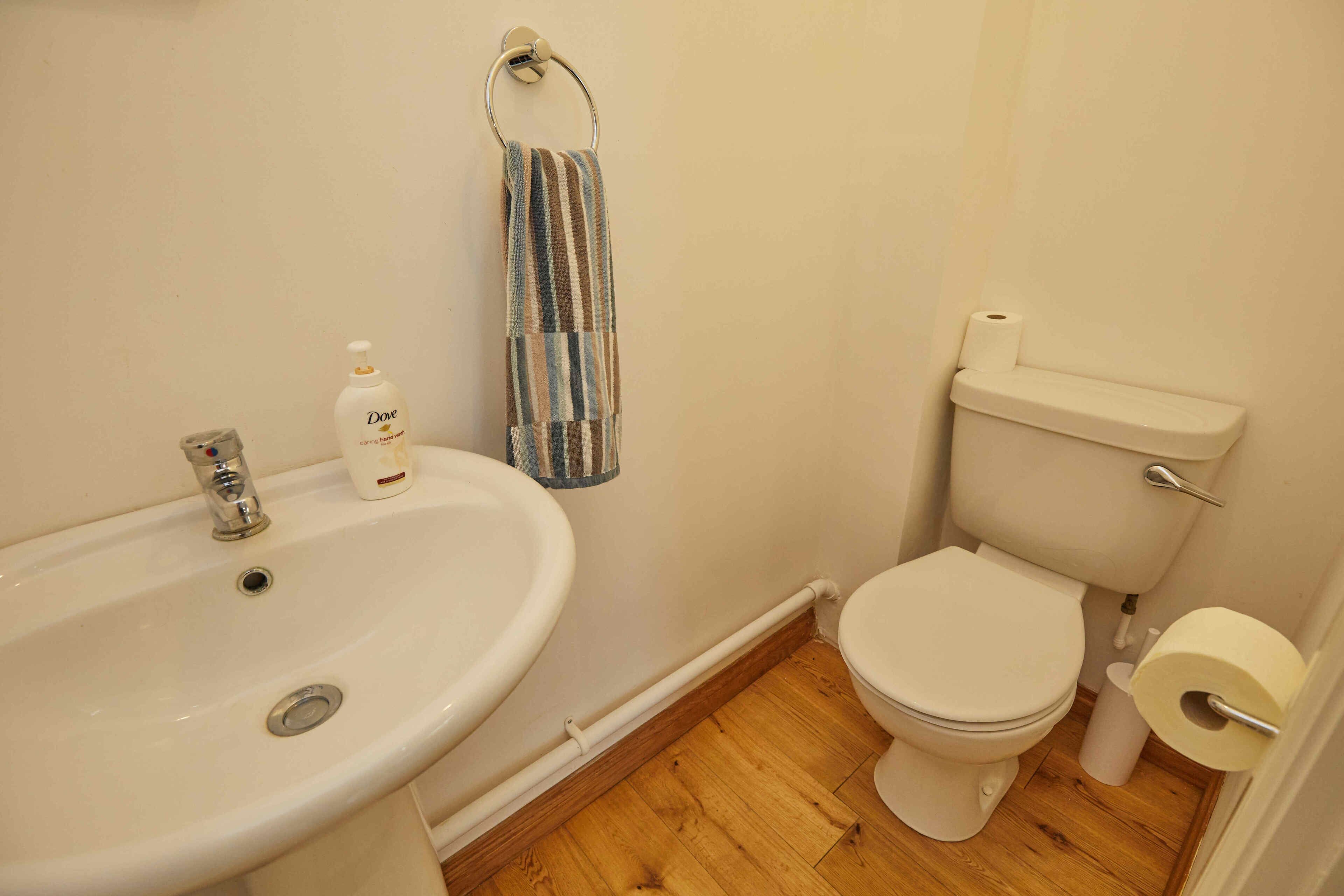 Ein Badezimmer mit Waschbecken, Toilette und einem gestreiften Handtuch an der Wand.