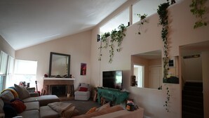 Un salon avec une cheminée, un téléviseur et un escalier.