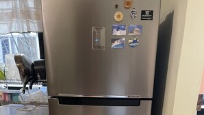 Un refrigerador de acero inoxidable con pantalla digital, un compartimento congelador y un dispensador de fácil acceso.