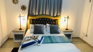 Una cama bien hecha con almohadas, una colcha y dos lámparas de noche, junto a un cabecero decorativo.
