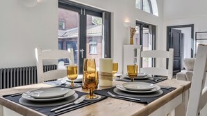 Ein Essbereich mit Tisch für vier Personen, gestaltet im modernen Stil, mit weißen Stühlen und einem Holztisch.