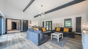 Una sala de estar moderna con un sofá gris, una mesa de centro y una cocina al fondo.