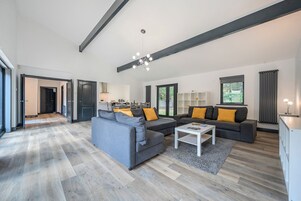 Una sala de estar moderna con un sofá gris, una mesa de centro y una cocina al fondo.