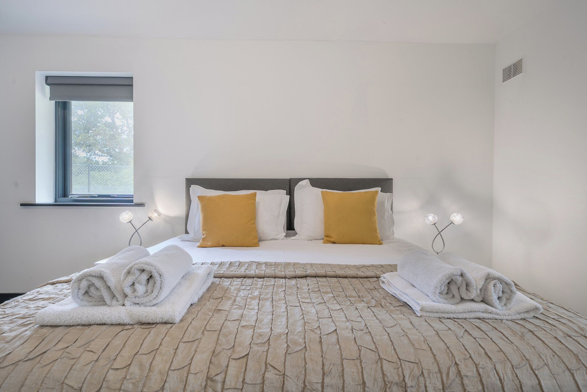 Habitación de hotel con cama, dos almohadas, ventana y dos lámparas de noche.