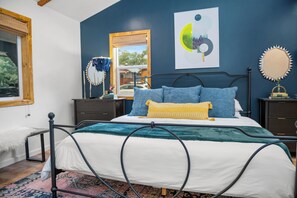 A bedroom with a bed, nightstands, a mirror, and artwork on the wall.