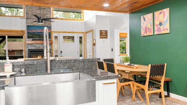 Una cocina moderna con encimeras de granito, pileta de acero inoxidable y mesa de comedor de madera con sillas.