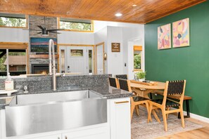 A modern kitchen with granite countertops, stainless steel sink, and wooden dining table with chairs.