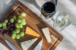 A wooden board with various cheeses and grapes, accompanied by glasses of wine. - JOIVY Charming 4-Bed House Near The Hoe Park (Plymouth)