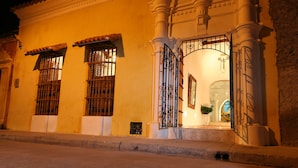 Un edificio histórico con fachada tradicional, que presenta una gran entrada arqueada, columnas decorativas y un tejado de tejas.