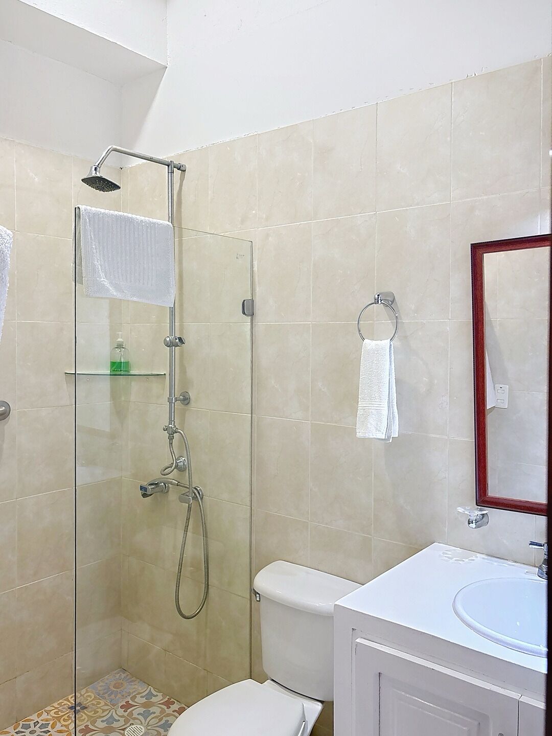 A bathroom with a glass-enclosed shower, a toilet, a sink, and a mirror.
