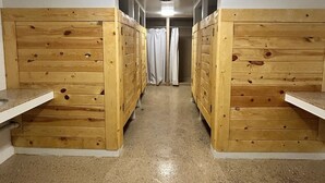 Um corredor com beliches de madeira em ambos os lados, que leva a um banheiro com cortina de chuveiro.