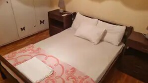 A bedroom with a bed, a nightstand, a wardrobe, and a bedside table. - Lovely 1-bed Apartment in Athina (Athens)