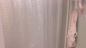 A bathroom with a shower curtain, a toilet, and a towel rack. - Lovely 1-bed Apartment in Athina (Athens)