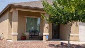 A residential building with a covered porch, a bench, a potted plant, and a tree.