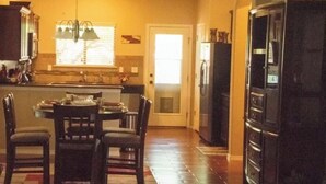 A kitchen with a dining table, chairs, and a refrigerator.