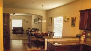 A spacious living room with a dining area, a kitchen with dark wooden cabinets, and a visible fire extinguisher.