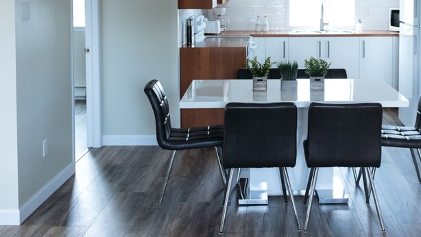 A modern kitchen with a central island, pendant lights, and a dining area with two chairs.