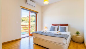 A bedroom with a bed, a bedside lamp, a small potted plant, and a view of a balcony. - Unique villa w/ pool by the Marina (Albufeira)