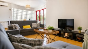 Un salon comprenant un canapé, une table basse, un téléviseur et une grande fenêtre donnant sur un beau paysage.