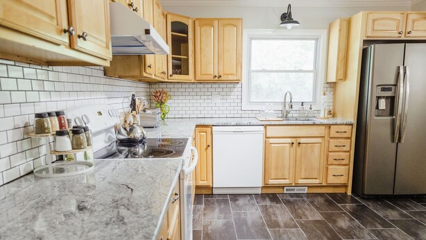 Una cocina moderna con armarios de madera, un refrigerador de acero inoxidable y un salpicadero de azulejos.