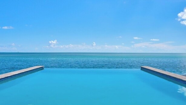 Un ciel d’un bleu éclatant surplombe une piscine d’où l’on peut admirer l’océan.