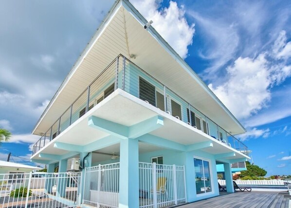 A modern two-story house with a balcony and a poolside area.