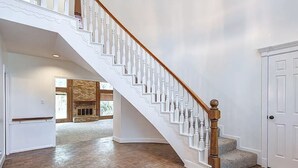 Un interior amplio con una escalera de madera, una chimenea y una puerta.