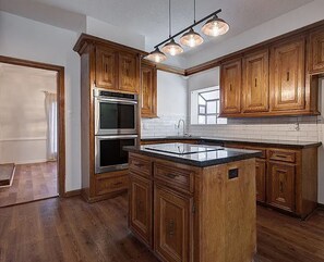 A kitchen with wooden cabinets, a central island, stainless steel appliances, and pendant lighting. - Stay at our Charming family home! (Houston)