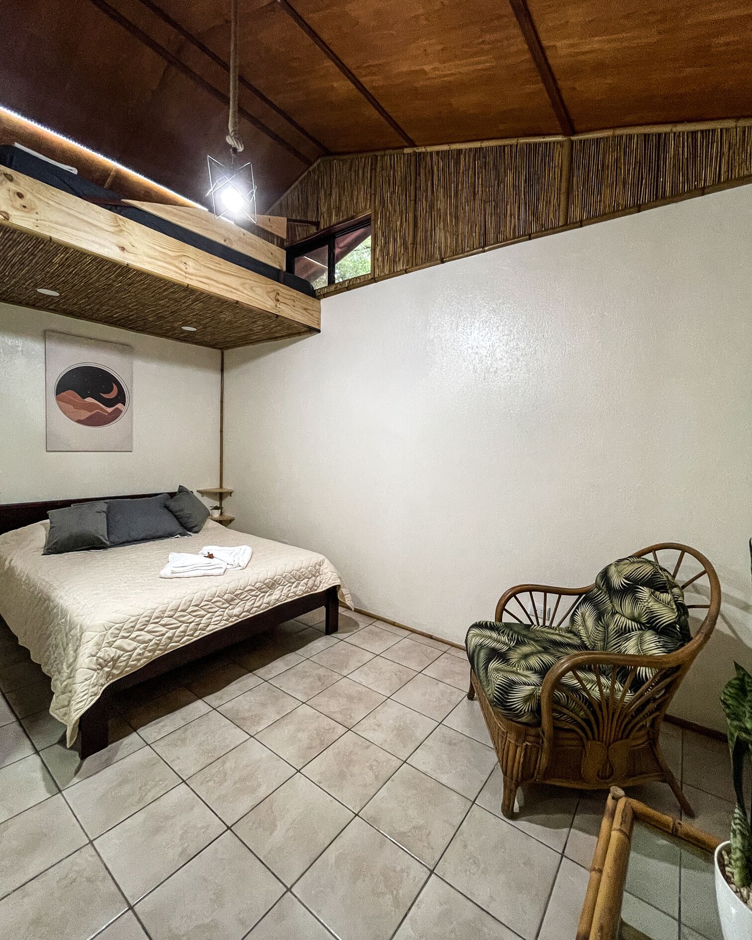 A bedroom with a bed, a chair, and a wall-mounted shelf.