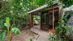 A modern, open-air structure with a wooden deck and glass walls, surrounded by lush greenery and a stone wall. - Terminal Verde (Concepcion)