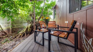 An outdoor patio with a wooden table and chairs, surrounded by greenery and a concrete wall. - Terminal Verde (Concepcion)