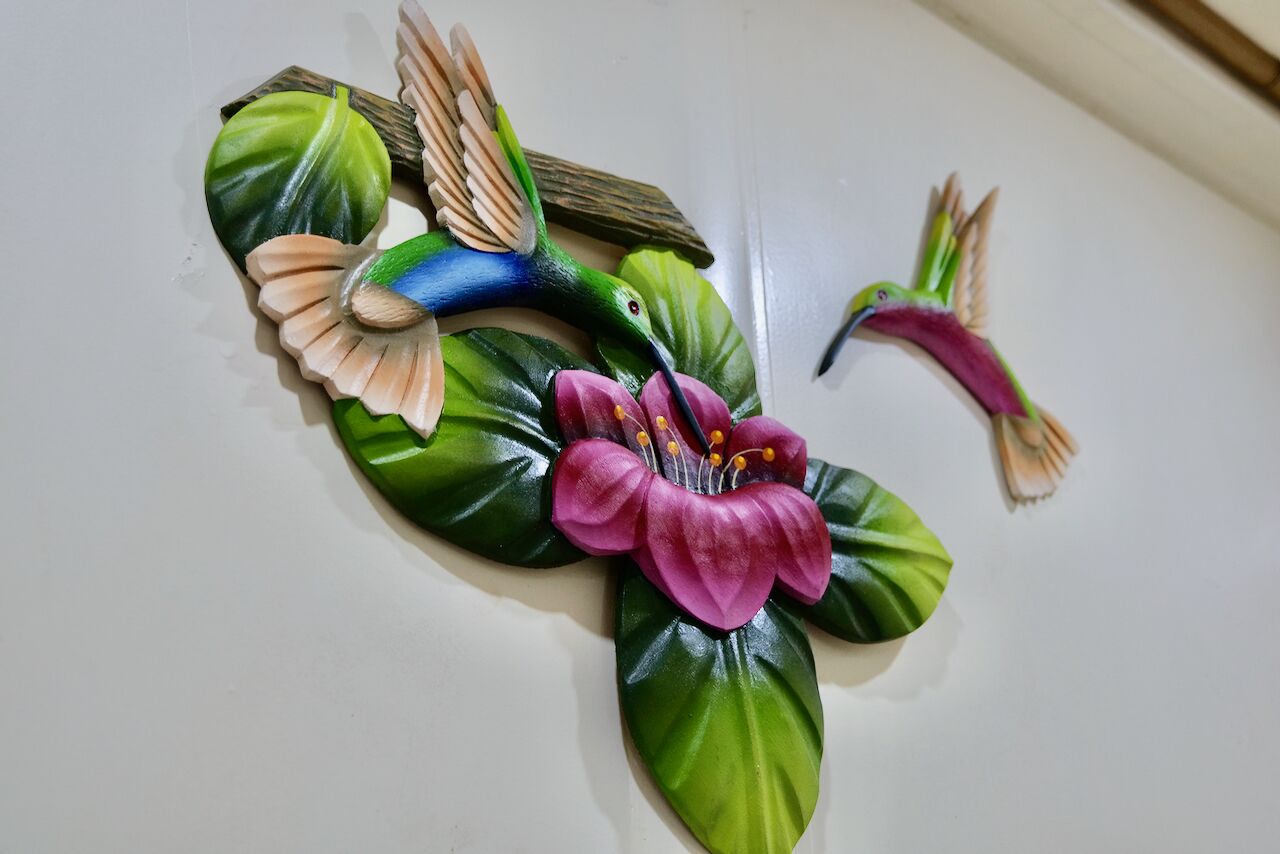 A decorative wall art featuring a hummingbird and a flower.