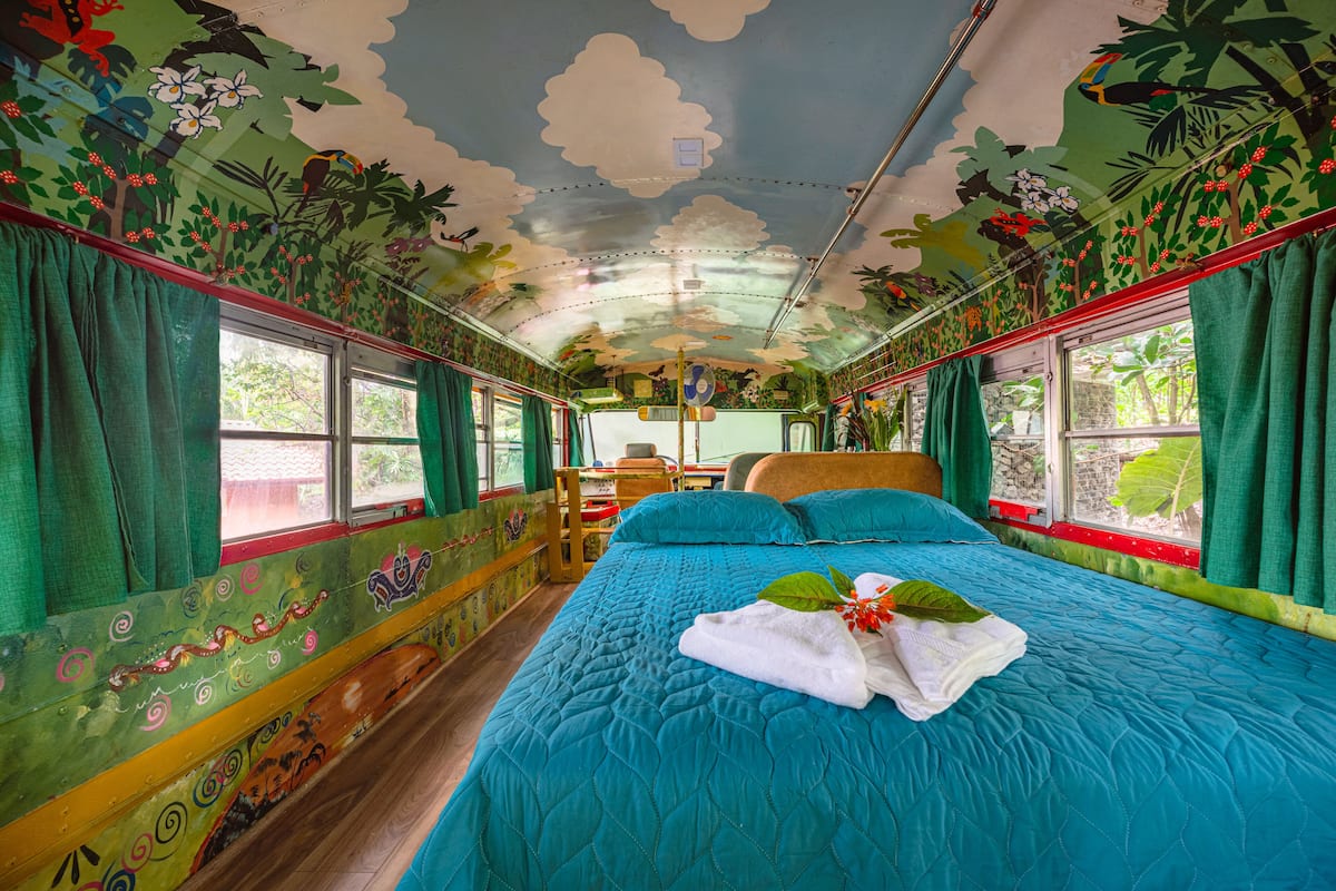 Quarto com cama, cortinas, janela e teto com mural.