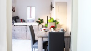 A modern dining area with a wooden table, two chairs, and a vase with a red flower.