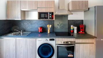 A modern kitchen with a washing machine, microwave, and coffee maker.