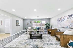 Relax in this stylish living room with a sofa set, wooden bench, and abstract art.