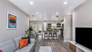 Ein modernes Wohnzimmer mit einem grauen Sofa, einem Flachbildfernseher und einem Marmortisch.