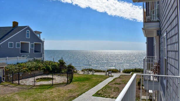 Een woonhuis met uitzicht op zee, een omheinde achtertuin en een balkon.