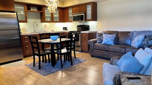 Una cocina moderna con armarios de madera, electrodomésticos de acero inoxidable y un comedor con mesa y sillas.
